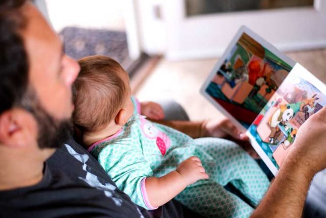 Stay-at-home dads reads book to baby.